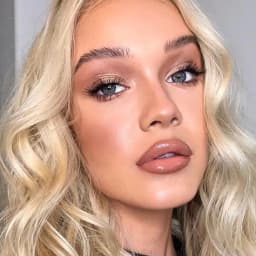 Maquillage glamour avec teint lumineux et effet glow, peau parfaite, yeux maquillés aux tons neutres et lèvres glossy nude, look beauté naturel et sophistiqué